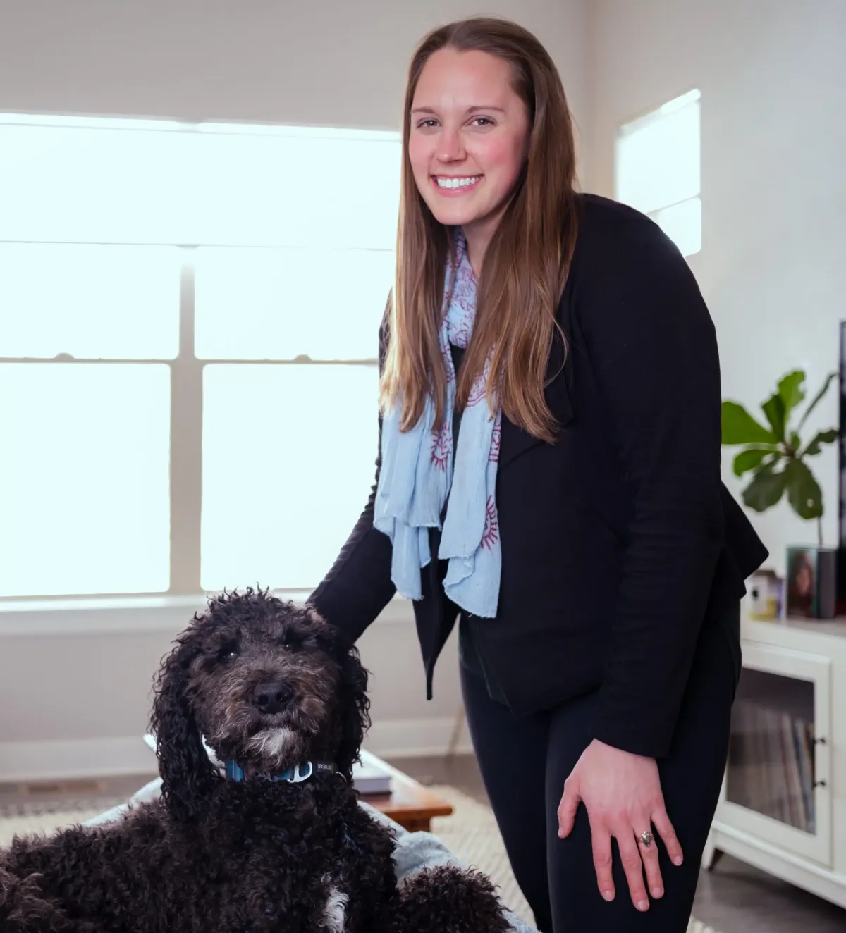 The Dashing Maids founder with a client's dog in a sunlit Denver living room